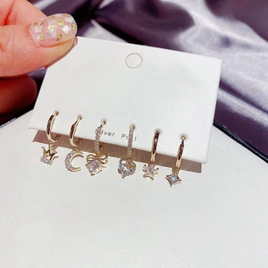 Detail of 6-piece gold earrings set with rhinestones featuring crown moon and star charms