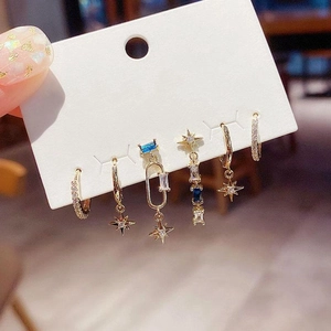 Close-up of a six-piece gold earring set featuring stars and blue cubic zirconia stones