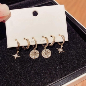 Detail of three pairs of gold star and moon tassel earrings set with zircon accents