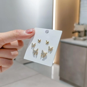Detailed close-up of golden butterfly earring set with sparkling white zircon stones