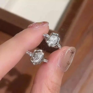 Macro view of silver Ruyi lock earrings featuring white cat eye stones and cubic zirconia