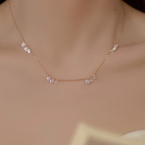 Détail du collier doré élégant avec quatre groupes de triple zircons porté par le modèle