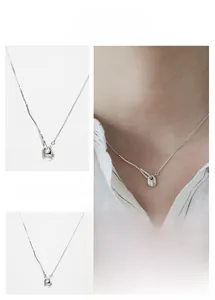 Detail of silver geometric weight pendant necklace on delicate box chain jewelry