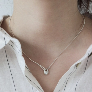 Minimalist geometric bean necklace on a model's neck with polished silver finish