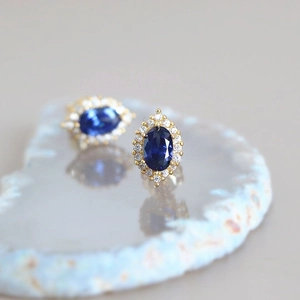 Boucles d'oreilles vintage avec pierres bleues ovales et halo de zircons sur marbre
