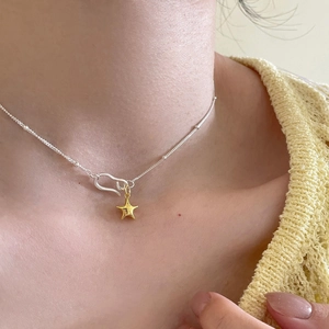 Minimalist gold star pendant necklace with delicate bead chain worn by a female model