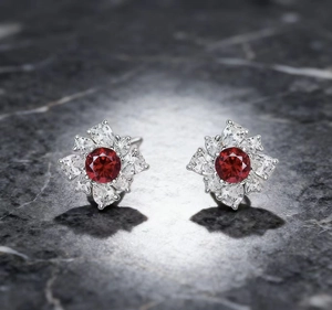 Close-up of flower stud earrings with red crystal center and sparkling clear zircon stones