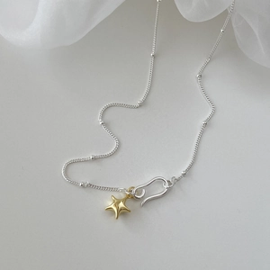 Detail of silver bead chain necklace featuring a gold star pendant and unique S-hook clasp