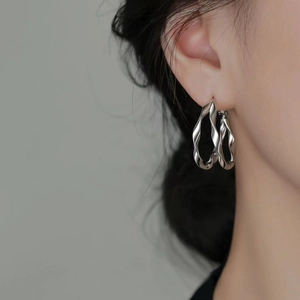 Double-layered silver twisted hoop earrings with a high-polish finish on female model