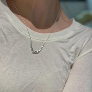Minimalist silver-toned U-shaped horn pendant necklace shown on a model neck