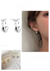Detail of elegant bow and heart stud earrings with Ear Partner engraving for women