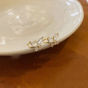 Close-up of gold butterfly earrings with sparkling cubic zirconia on white ceramic tray