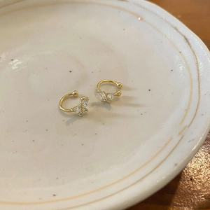 Detailed close-up of gold butterfly ear cuffs with micro-set cubic zirconia on a ceramic dish