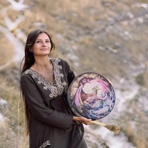 Close-up of ethnic dragon pattern drum held by a person outdoors with drumstick