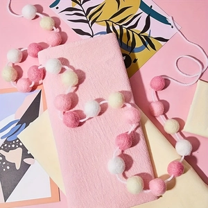 Guirlande de boules de feutre rose et blanc sur tissu pour décoration de fête maison