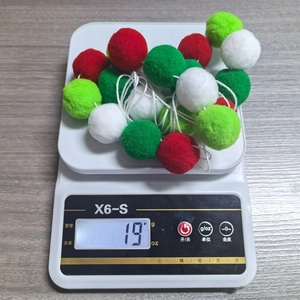 Detail shot showing a 19g weight measurement of a 2m Christmas pompom garland on a scale