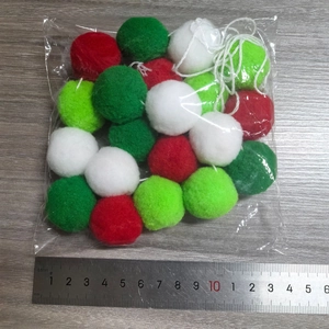 Detail of 2cm red and green felt ball garland with a ruler for size reference