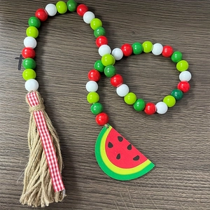 Detail of watermelon wood bead garland featuring a natural jute tassel and painted slice charm