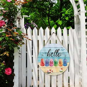 Close-up of Hello Summer round wooden sign hanging on a white fence with pink roses