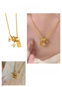 Dettaglio della collana dorata con ciondoli stella, luna, sole e piastrina rettangolare