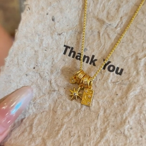 Elegante collana dorata con ciondoli a luna, stella e cuore su un biglietto di ringraziamento