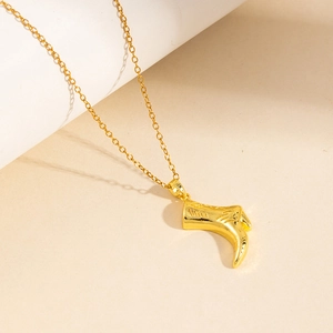 Gros plan du pendentif botte dorée avec gravure rayée sur une fine chaîne à maillons