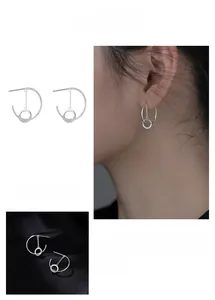 Close-up of geometric C-shaped hoop earrings with delicate chain and micro-inlaid zircon