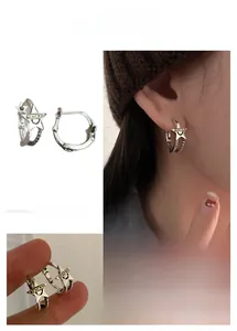 Detail of silver star hoop earrings featuring golden Lucky plate and hollow design