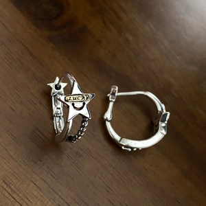 Detail of S925 silver star hoop earring with Lucky engraving on a wood surface