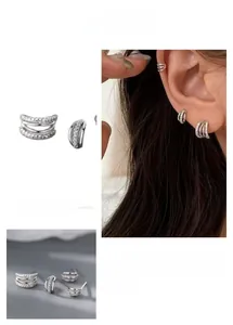 Close-up of geometric C-shaped multi-layer stud earrings with pave-set zircon stones