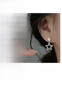 Detail of star-shaped zircon earrings with hollow design and shiny silver finish