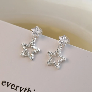 Macro shot of silver star drop earrings with sparkling zircon inlay and textured finish