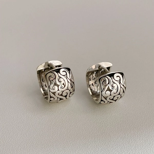 Macro view of vintage silver hoop earrings featuring hollow geometric filigree patterns