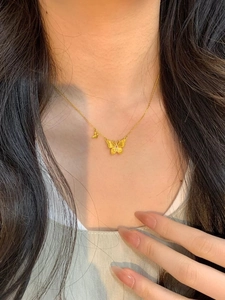 Détail d'un collier papillon doré vintage à double couche avec une pierre rouge