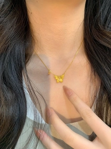Gros plan d'un collier papillon doré avec texture mate et une pierre rose précieuse