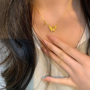 Collier papillon vintage avec pierre rouge porté par un mannequin de mode chic