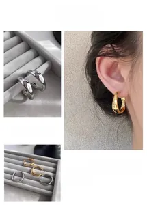 Detail view of geometric metal hoop earrings in gold and silver with model shot