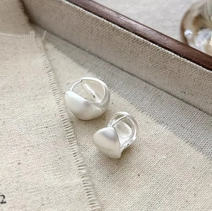 Minimalist brushed silver teardrop earrings on a natural linen and wood background