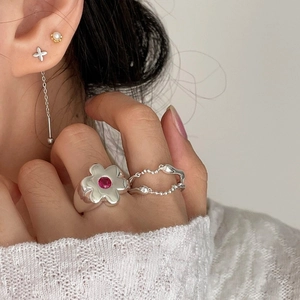 Silver flower ring with red stone and layered bead chain ring on a model