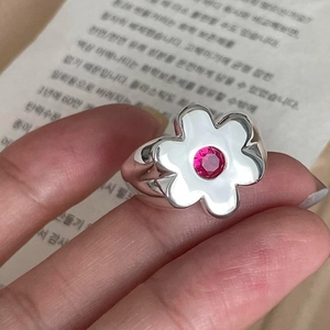 Detailed close-up of a silver flower ring with white petals and a pink gemstone center