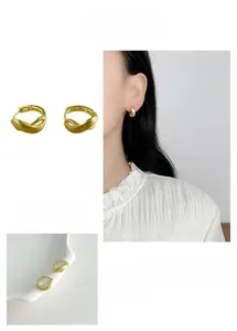 Detail of matte gold crisscross hollow hoop earrings with textured irregular finish