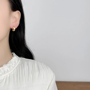 Minimalist twisted gold hoop earrings with matte finish shown on a female model