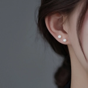 Close-up of starburst texture on round silver stud earrings worn by a model