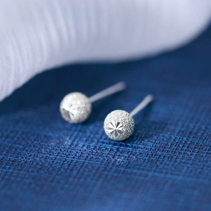 Minimalist silver spherical stud earrings with matte finish and laser star pattern