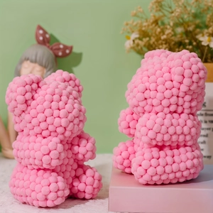 Close-up of pink pom-pom teddy bear figurines with soft plush texture on lace tablecloth