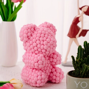Pink pom-pom bear figurine displayed with spring flowers and elegant home decor items