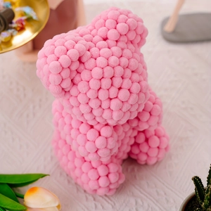 Detailed top view of pink pom-pom bear figurine with decorative flowers and props
