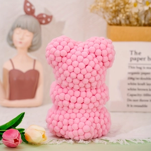 Detailed view of a pink pompom bear figurine on a lace tablecloth with tulips