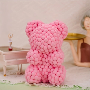 Detailed view of a handmade pink pompom bear doll on a decorative aesthetic desk setup