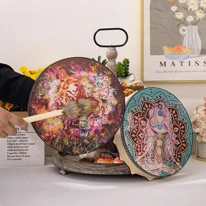 Detailed close-up of handmade Shaman drums with tiger and goddess patterns on a table